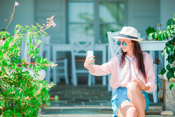 Fototapeta premium Young beautiful woman taking selfie with phone in outdoor cafe