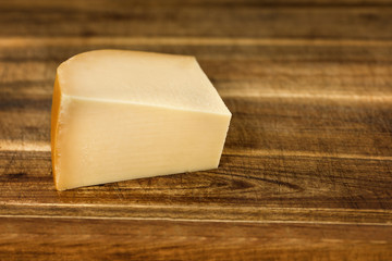 Piece of mellow yellow cheese on a rustic wooden board - food, breakfast, brunch, rustically 