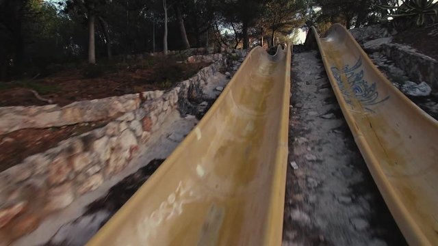 Drone flights low and quickly in creepy abandoned aquatic park between destroyed plastic water rides in forest