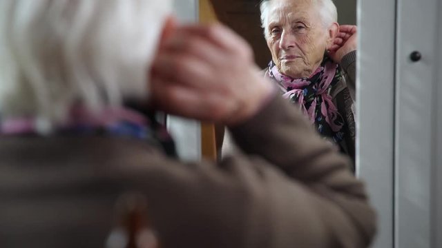 sad and depressed old woman in the mirror touches hair