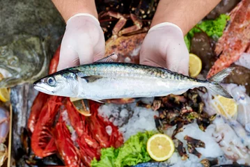 Crédence de cuisine en plexiglas Poisson Vendeur présentant un poisson maquereau en poissonnerie