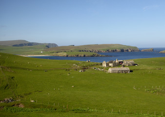 Naklejka premium Rustic stone buildings sitting in lush green fields near sea