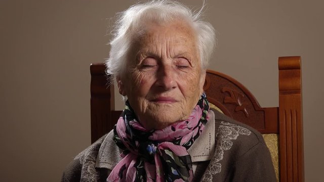 old grandmother sitting looking at the camera and closes her eyes