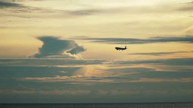  Plane landing in silhouette against an dusky orange sky at Phuket International airport, Thailand. Slow motion video.

