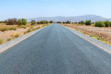 Clear road in Moroccan desert. Nobody. Mountains on horizon