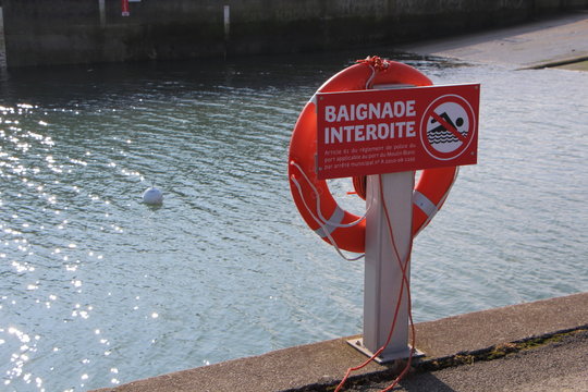 Panneau baignade interdite et bou&eacute;e de sauvetage sur un quai 