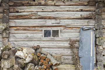 Heap of chopped logs for firewood near old wooden wall