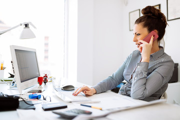 Obraz premium Happy businesswoman working at her desk