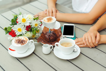 Chocolate muffin with one candle, cups with coffee on wooden table .