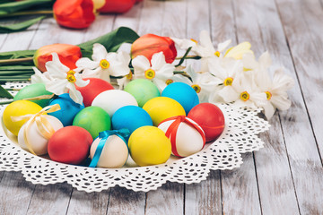 Obraz na płótnie Canvas Easter background. Colored easter eggs and spring flowers on white wooden background.