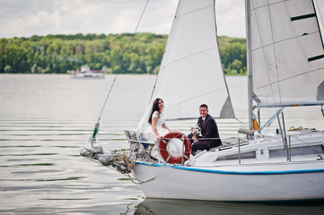 Wedding couple in love at small sailboat yacht on lake.