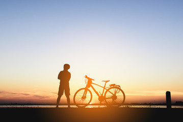 Silhouette of a biker  on the hill with sunset background, enjoying freedom and active lifestyle, having fun on a bikers tour