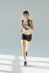 Fototapeta na wymiar front view of running woman in sportive clothing on grey
