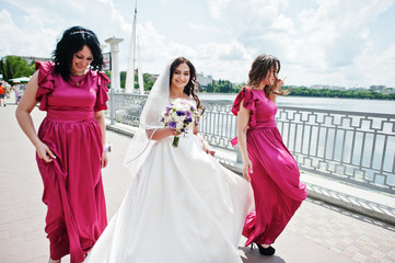 Bride walking and having fun with charming bridesmaids on rose dresses.