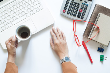 Businesswoman holding cup of coffee on modern white office table, Flat lay