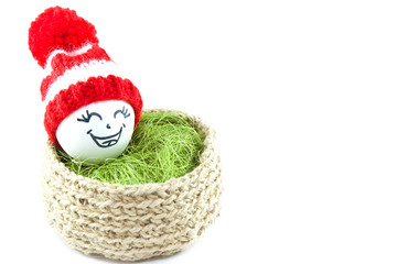 Easter eggs in a basket. Emoticons in knitted hats with pom-poms. Knitted basket of jute, sisal green. Handmade.