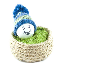 Easter eggs in a basket. Emoticons in knitted hats with pom-poms. Knitted basket of jute, sisal green. Handmade.