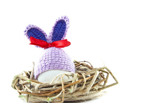 Easter eggs in the nest. Knitted Easter Bunny. Egg in Easter bunny cap.
