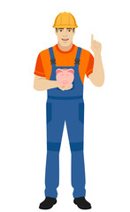 Builder holding a piggy bank and pointing up