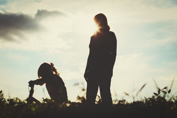 mother teaching little daughter to ride bike at sunset