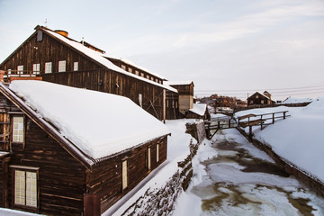 An old, copper mine smelting building near the river in the winter Norway town