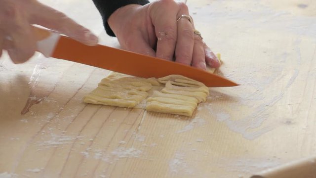 woman's hand cut the dough to make noodles