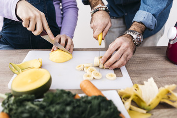 Hands of couple chopping fruits for preparing smoothies