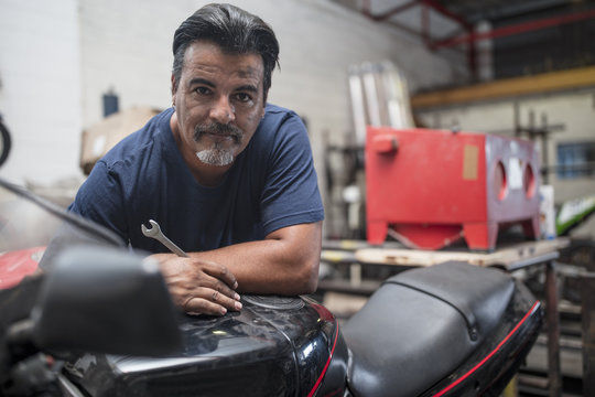 Portrait of confident mechanic in motorcycle workshop
