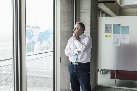 Businessman looking at windowpane with world map in office