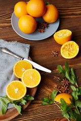 Directly above view of rustic wooden kitchen table with fruits and spices on it, all set for making mullet wine: fresh ripe oranges cut in half, mint and star anise scattered in elegant assortment