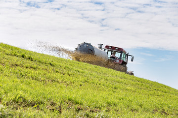 Traktor fährt mit Güllewagen in Hanglage