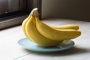 Yellow bananas on blue plate on  wooden background
