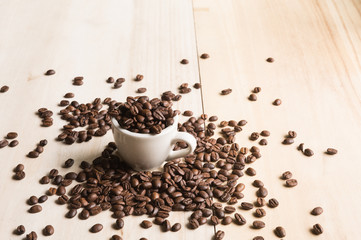 Cup full of coffee beans on wood background