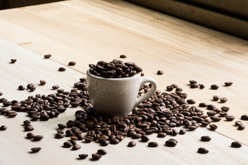 Cup full of coffee beans on wood background