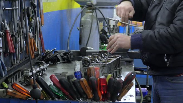 hands of mechanic uses allen key on his work table