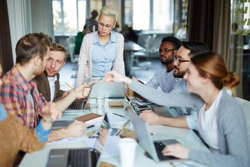 Enthusiastic male and female programmers creating new computer application while sitting in boardroom with glass wall