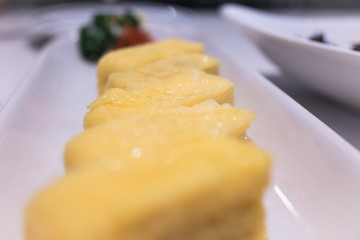 Dashimaki Tamagoyaki, Japanese omelette on white plate with green vegetable