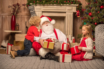 Obraz na płótnie Canvas Santa Claus and children with Christmas gifts