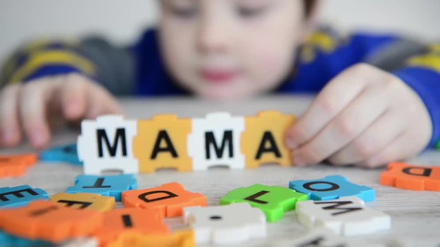 boy made word mama from letters on colorful puzzles