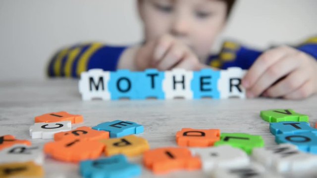 boy made word mother from letters on colorful puzzles
