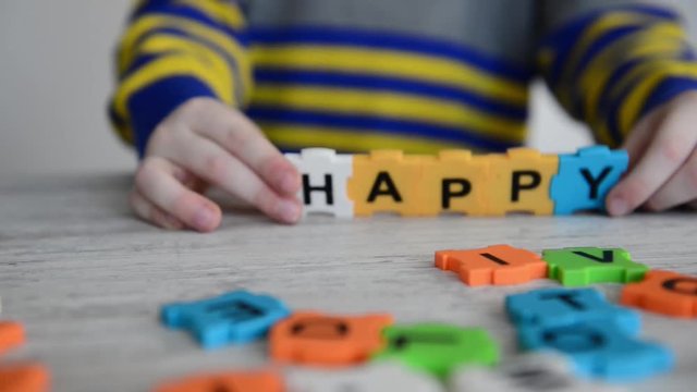 boy made word happy from letters on colorful puzzles