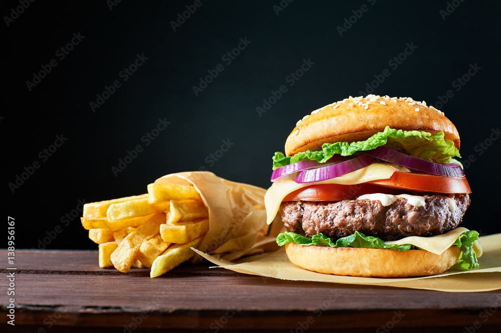 Wall mural craft beef burger and french fries on wooden table isolated on black background.