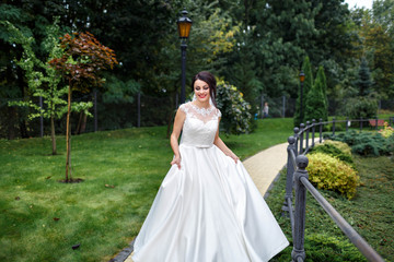 Fototapeta premium beautiful and young bride in white dress walking in the garden
