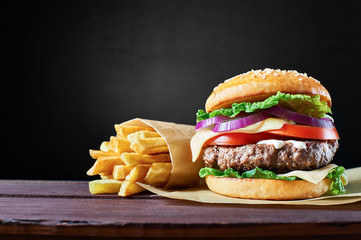 Craft beef burger and french fries on wooden table isolated on black background. - Powered by Adobe