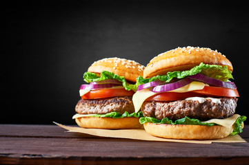 Two craft beef burgers on wooden table isolated on black  background.