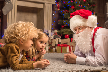 Fototapeta na wymiar Children and Santa Claus lying on carpet