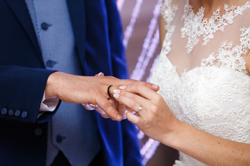 Obraz na płótnie Canvas bride wearing the golden ring on finger of her husband