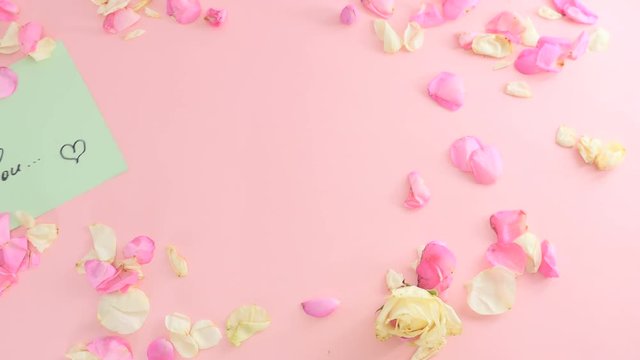 Yellow sheet of paper moving among the rose petals on pink background