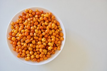 White plate of sea buckthorn on the white table
