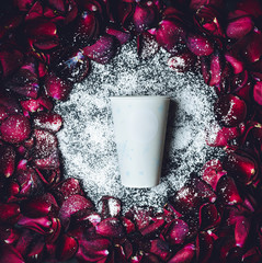 White paper cup lies in white powder in the circle of red rose petals